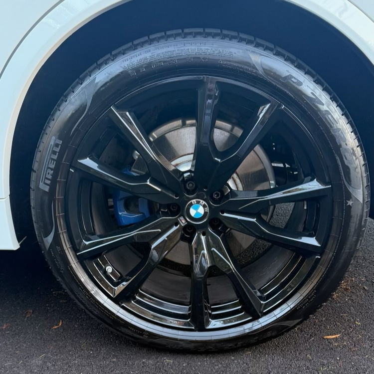 BMW alloy wheel after — deep gloss black finish with clean spokes and dressed tyre