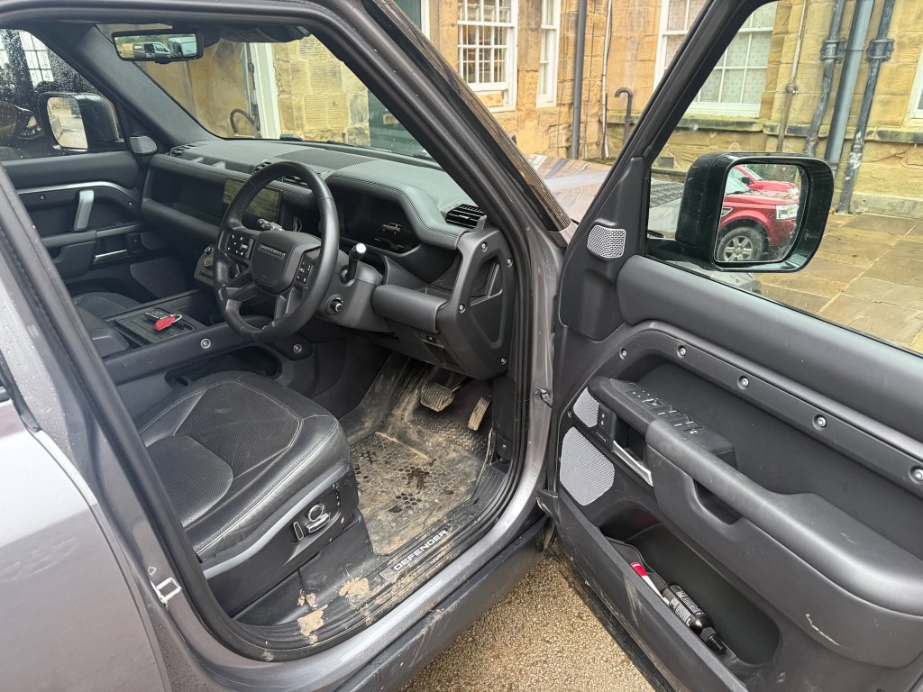 Defender interior before — heavily soiled floor mats with mud and dirty door sill